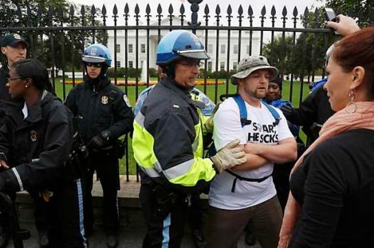 Law enforcement officers force protesters down from the fence in front of the White House gates in Washington